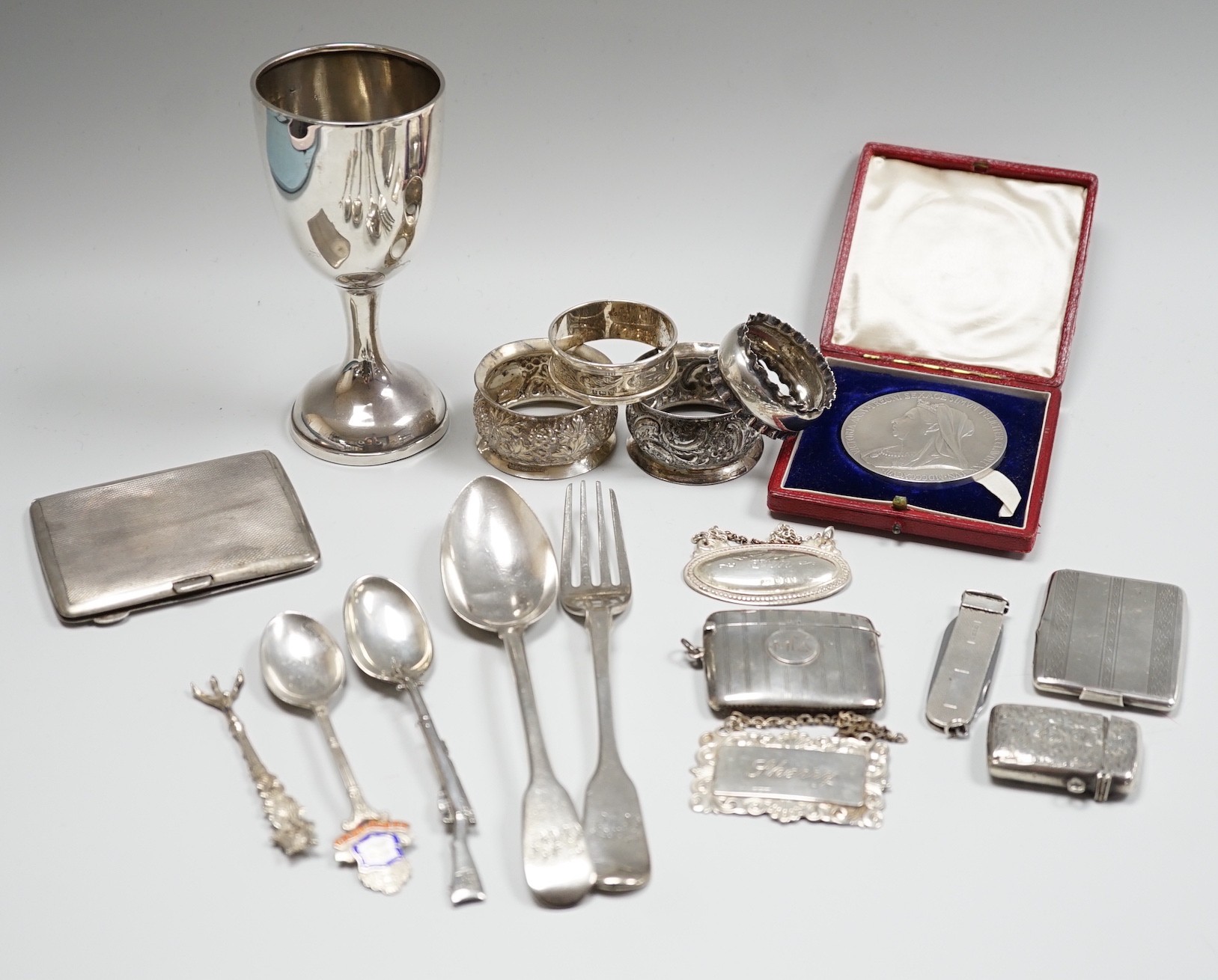 Sundry small silver including a George V goblet, cigarette case, vesta cases, flatware, wine labels and napkin rings including plated.